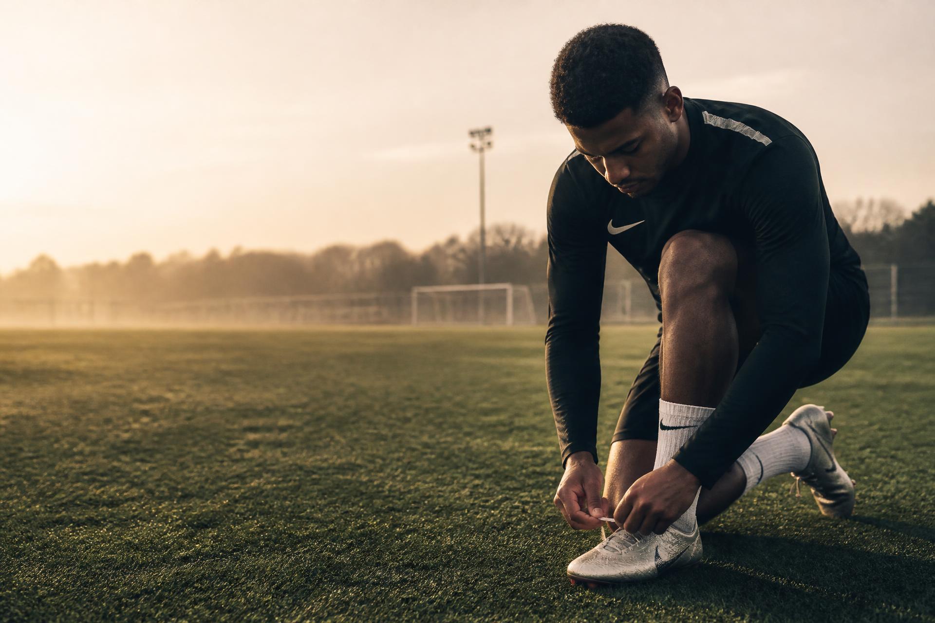 Footballeur laçant ses crampons sur un terrain à l'aube